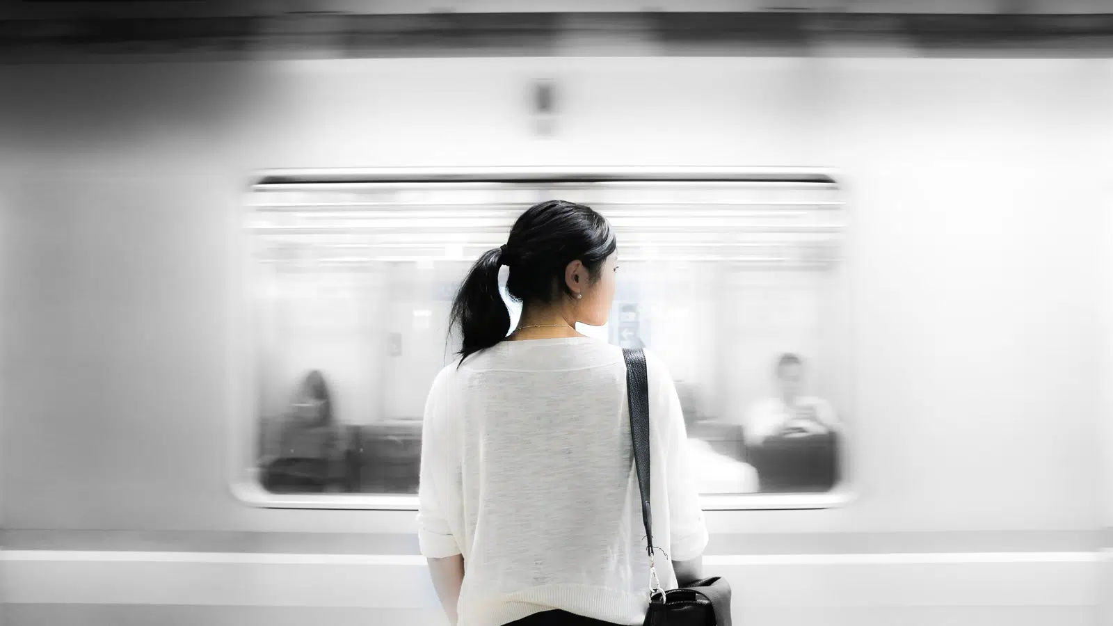 Frau auf Bahnsteig vor fahrendem Zug